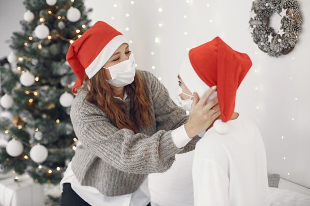 母亲为圣诞节做准备的人冠状病毒主题妈妈和儿子玩穿白毛衣的男孩毛衣节日花环