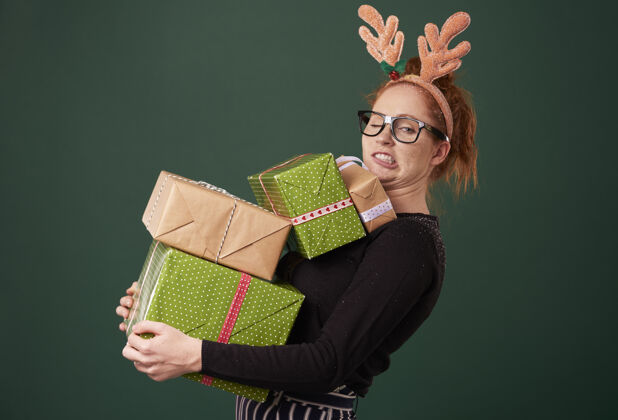 使一张脸有趣的女人拿着一堆圣诞礼物购买努力女人