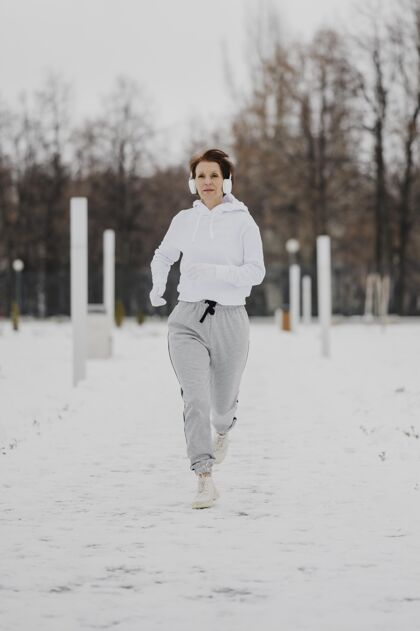 运动在雪地里奔跑的全副武装的女人健身锻炼活动