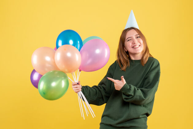 女人正面图：带着彩色气球的年轻女性乐趣年轻颜色