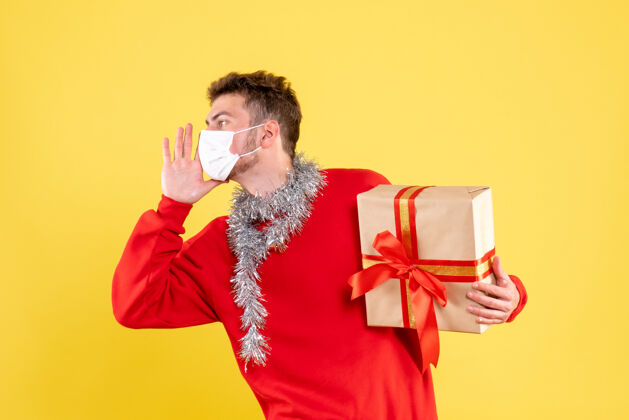 不育正面图：年轻男性手持无菌面具在呼唤圣诞礼物成人男性肖像