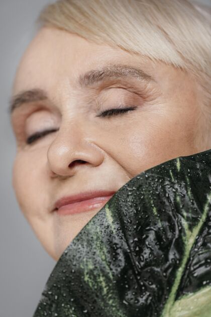 养老金领取者特写微笑的女人拿着树叶自然护理灰色