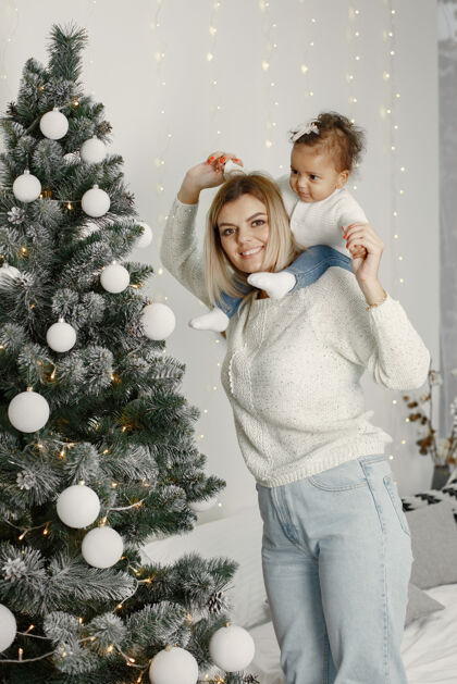花环人们在为圣诞节做准备母亲在和女儿玩耍一家人在节日的房间里休息孩子穿着毛衣圣诞节国际女儿