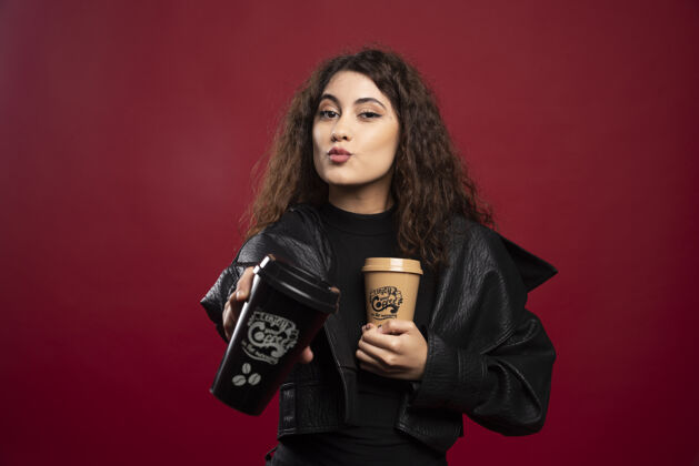 美丽一个穿全黑衣服的年轻女人 展示着两个杯子优雅咖啡外卖