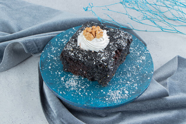 糕点巧克力蛋糕涂上香草粉在大理石背景上的一块小木板上蛋糕巧克力糖