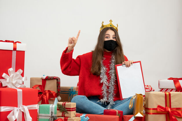 黑穿着红色毛衣的年轻女孩围坐在礼物旁边 白色的面具上戴着黑色的面具圣诞节包礼物