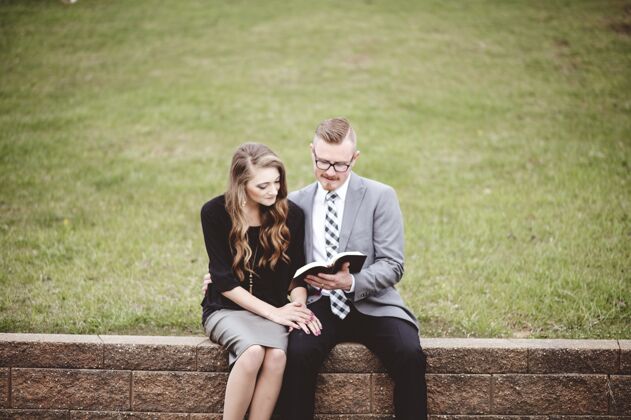 文化一对穿着正式衣服的夫妇在花园里一起看书的情景老高加索成人