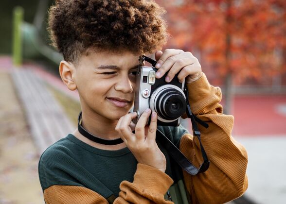 乐趣小男孩用相机拍照相机水平公园