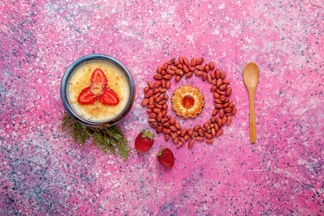 浆果顶视图美味的奶油甜点与红色切片草莓和花生上的浅粉色背景甜点冰淇淋颜色甜水果浆果花生细菌背景