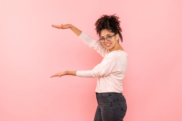 情感一位年轻女子在粉色墙上展示身材的正面图开朗美丽健康