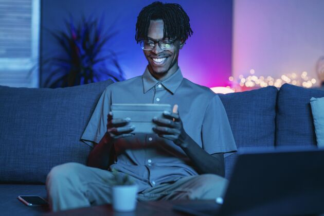 水平快乐的人在家里沙发上用他的平板电脑科技笔记本电脑科技