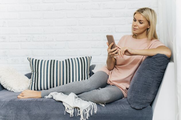 病毒大流行期间 沙发上的女人在家里用智能手机流行病预防隐居