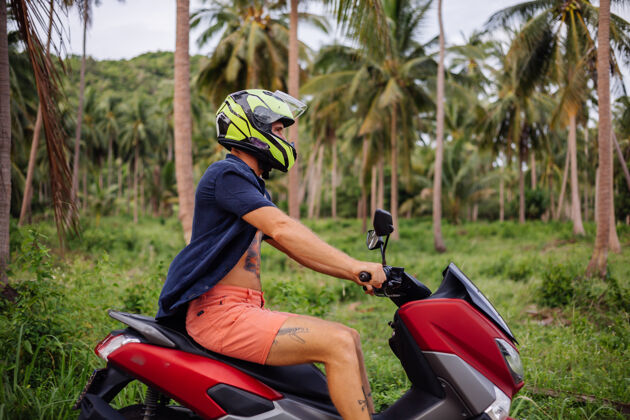 户外在热带丛林的田野上纹着红色摩托车的壮汉景观度假人