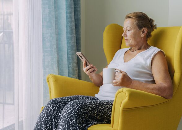 隔离大流行期间 一位老妇人在家喝咖啡时使用智能流行病冠状病毒