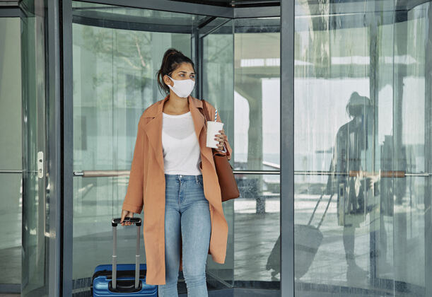 机场大流行期间在机场带着行李和医用口罩的女人运输Ncov病毒