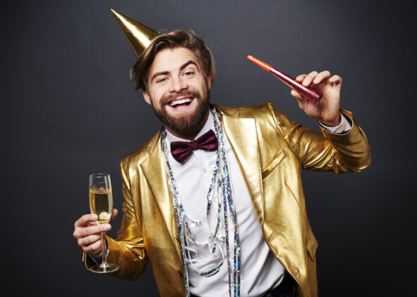 男人手持香槟长笛和派对吹风机的微笑男人的肖像鞠躬庆祝聚会