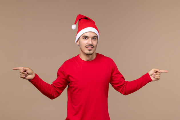 男性正面图年轻男性在棕色背景上摆姿势圣诞节风景快乐节日