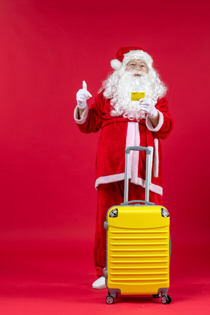 男人红墙上拿着黄色银行卡的黄色袋子的圣诞老人的正视图圣诞服装十二月