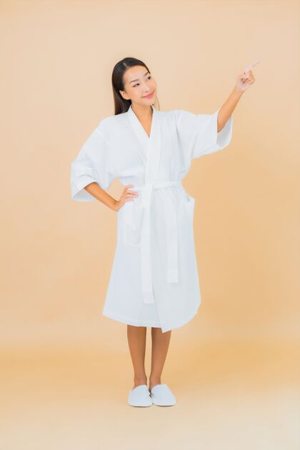 自然肖像美丽的亚洲年轻女子穿着米色的微笑浴袍毛巾清洁诊所
