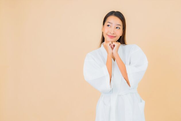 模特肖像美丽的亚洲年轻女子穿着米色的微笑浴袍护理亚洲浴缸