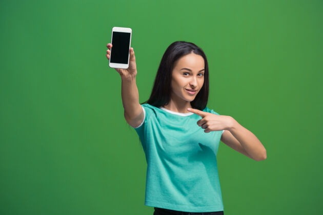 手机一个微笑的女人的肖像显示空白的智能手机屏幕上的绿色隔离肖像空白手