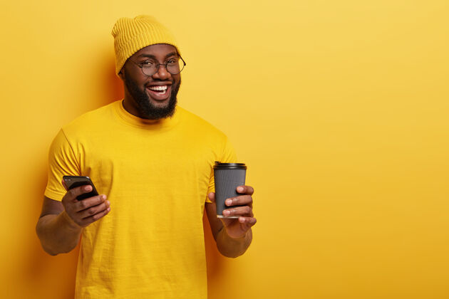 手机很高兴非裔美国人在社交网络上阅读新闻 享受一次性杯子里的热饮摩登短信咖啡