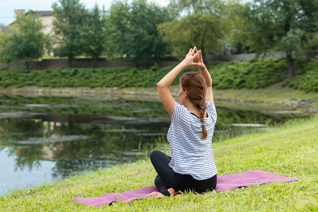 健身年轻漂亮的女人在绿色公园做瑜伽练习健康的生活方式和健身理念成人女性女孩