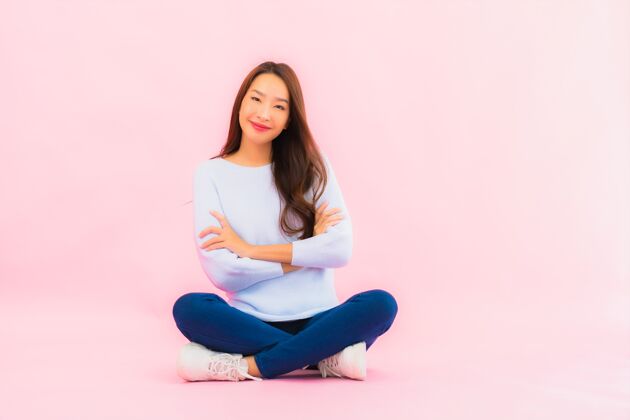 销售肖像美丽的亚洲年轻女子坐在粉色隔离墙的地板上合作信任女士