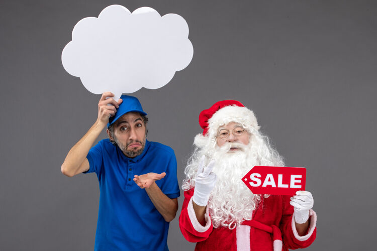 十二月圣诞老人的正面图 男信使手持白云招牌 在灰色墙上出售男性圣诞老人人