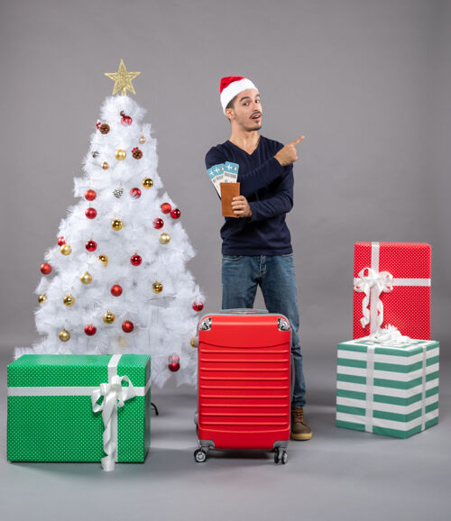 圣诞老人一个拿着红色手提箱的男人拿着他的旅行票 用手指着灰色的东西圣诞帽东西灰色