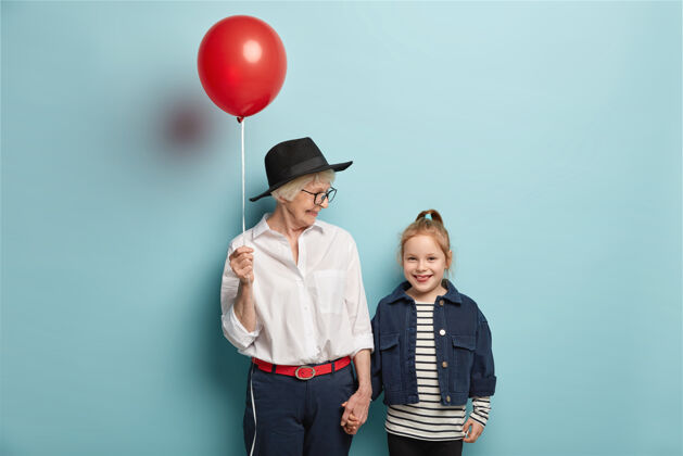 马尾辫慈祥的奶奶用开学的第一天祝贺小朋友的半身镜头 捧着红气球有着幸福的表情快乐的奶奶 孙女从马戏表演回来的好心情退休周末微笑