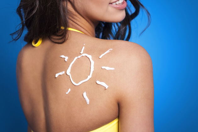 黄色晒黑乳液在女人的手臂上晒成太阳形状润肤霜绘画向上