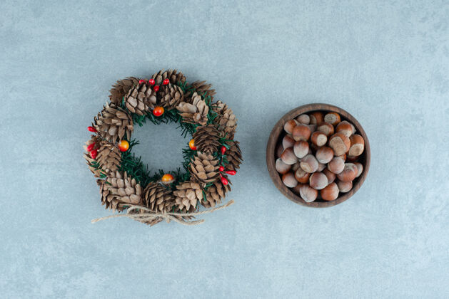 视图松果花环和一碗榛子放在大理石上顶部顶部视图圣诞节