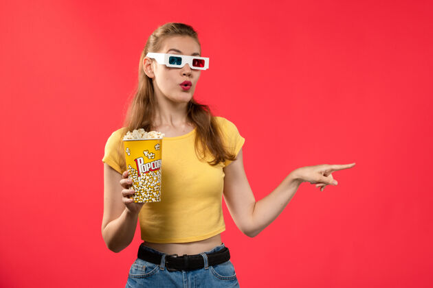 年轻人前视图年轻女性在电影院拿着爆米花在-d太阳镜在红墙电影院小吃好玩的电影电影院女性电影