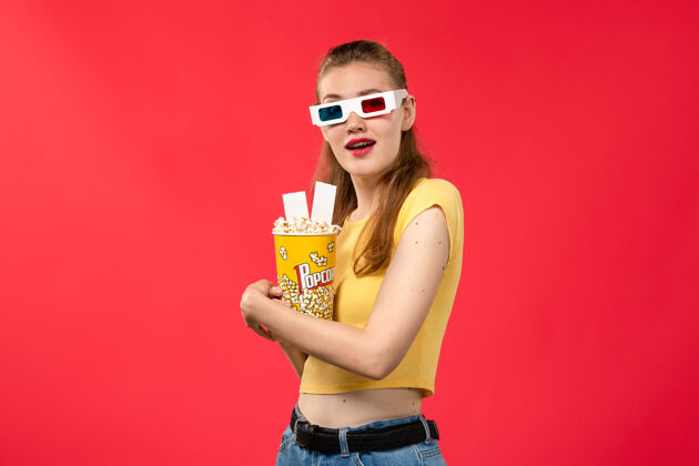 电影正面图年轻女性在电影院里拿着爆米花在浅红的水面上电影院里女性的颜色风景年轻剧院