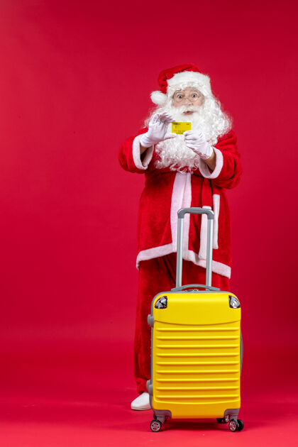 举行红墙上拿着黄色银行卡的黄色袋子的圣诞老人的正视图快乐前面冬天