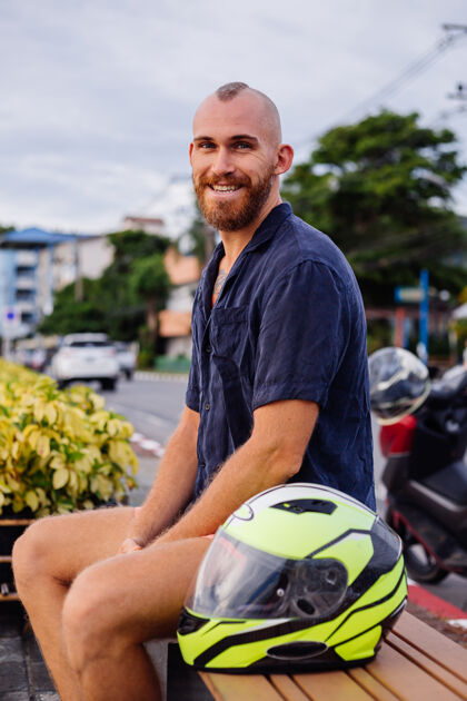 骑日落时分坐在泰国长廊长凳上的戴着黄色头盔的男性摩托车手的画像引擎交通工具速度