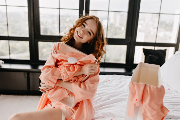 微笑迷人的红发女孩在卧室里摆姿势室内拍摄的姜黄色头发的迷人女模特享受早晨睡衣快乐可爱
