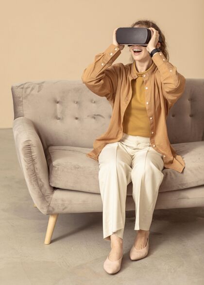 肖像坐在沙发上玩虚拟现实耳机的女人模特工作室摄影