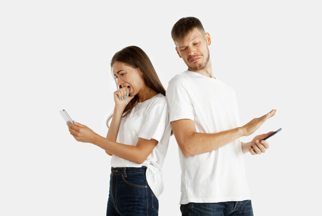 年轻美丽的年轻夫妇的肖像面部表情 人类的情感男人和女人拿着智能手机 看起来害怕它的屏幕肖像可爱表情