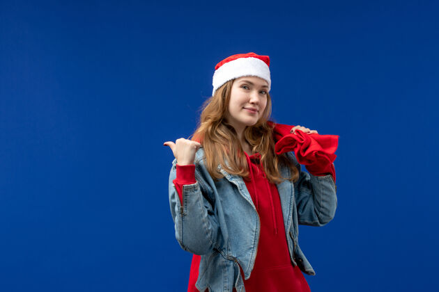 前面正面图：蓝色空间里 年轻的女性拎着装满礼物的袋子帽子快乐蓝色