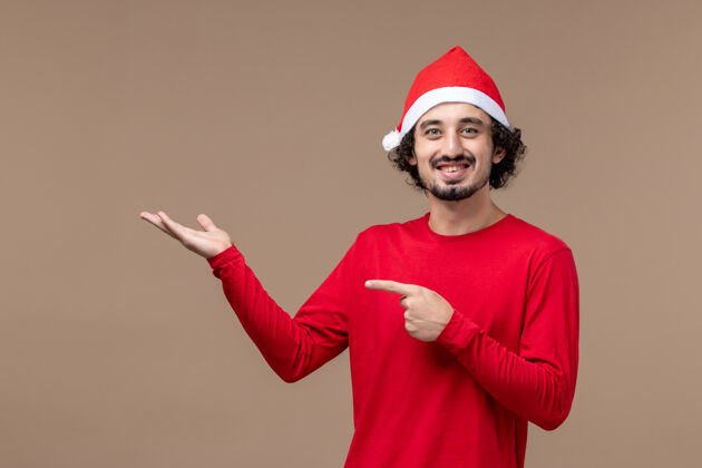 肖像正面图：棕色背景上穿着红色圣诞斗篷的年轻男性 感慨节日圣诞节微笑背景微笑