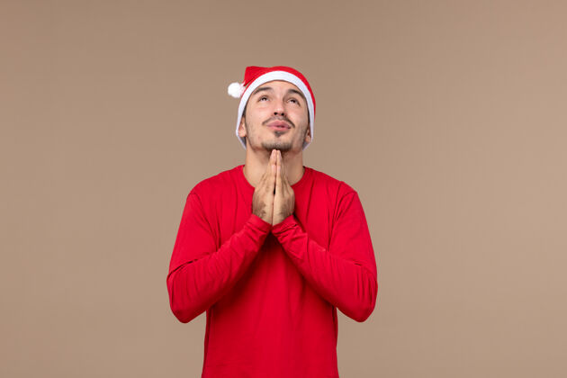歌手正面图：年轻男性在棕色背景下祈祷圣诞节圣诞节表情肖像