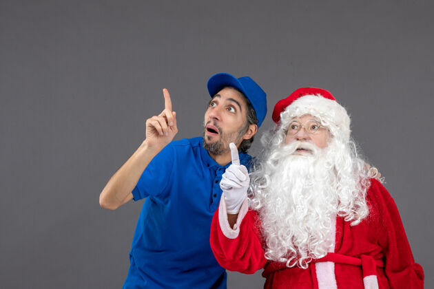 信使灰色墙上的圣诞老人和男信使的正面图庆祝节日快乐