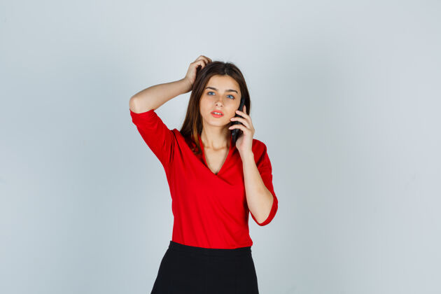 美丽穿红衬衫 裙子的年轻女士在讲手机休闲欧洲肖像