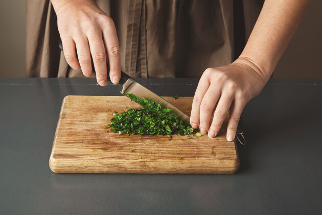 食物老蓝桌上的木板上 女人们用手剁欧芹特写健康晚餐蔬菜