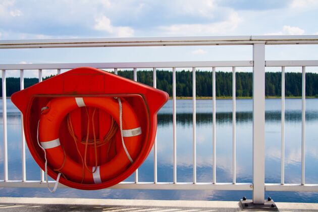 墙一个红色救生圈挂在桥的白色栏杆上的特写镜头窗木游泳