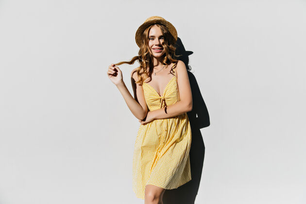 影子穿着黄色衣服的温文尔雅的女孩玩着她卷曲闪亮的头发有兴趣优雅的女人在夏日帽子里摆姿势优雅苗条积极