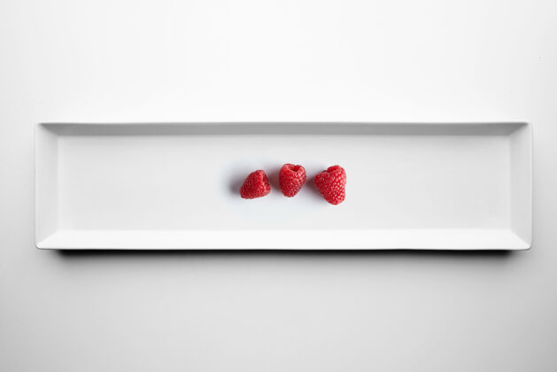 樱桃三个树莓被隔离在白色陶瓷板上菜肴素食主义者早餐