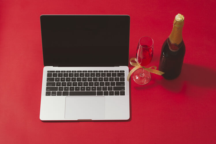 酒精平放 顶视图办公桌红色表面上有笔记本电脑和圣诞装饰品的工作区圣诞节灯玻璃
